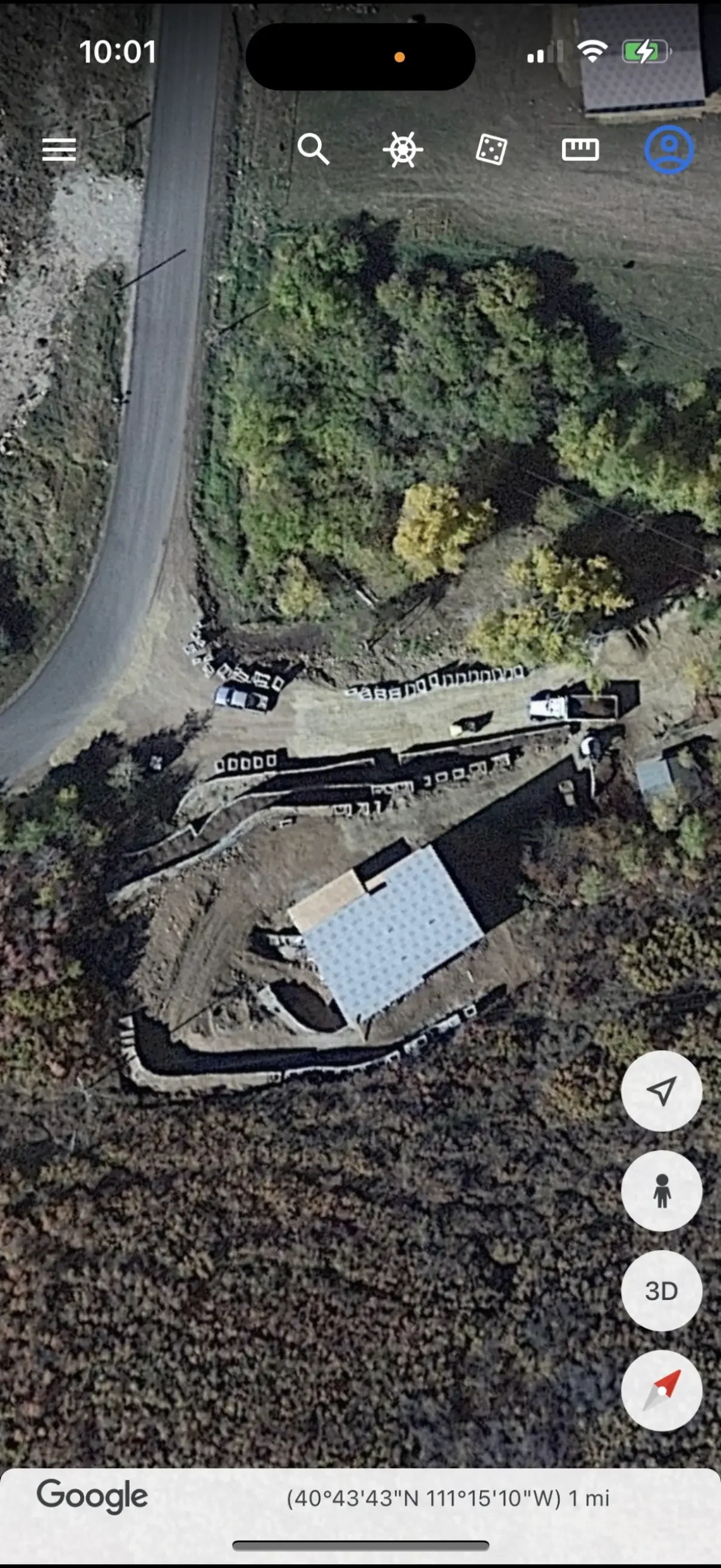 Aerial view of excavation site with stacked block retaining walls, graded terraces, and dump truck on cut slope